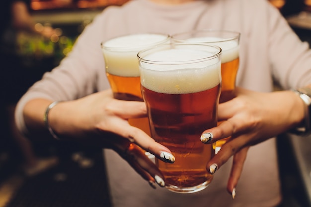 Woman holding three glasses of beer