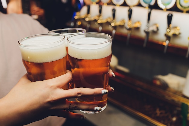 Woman holding three glasses of beer