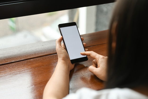 Woman holding and touching white screen mockup smartphone.