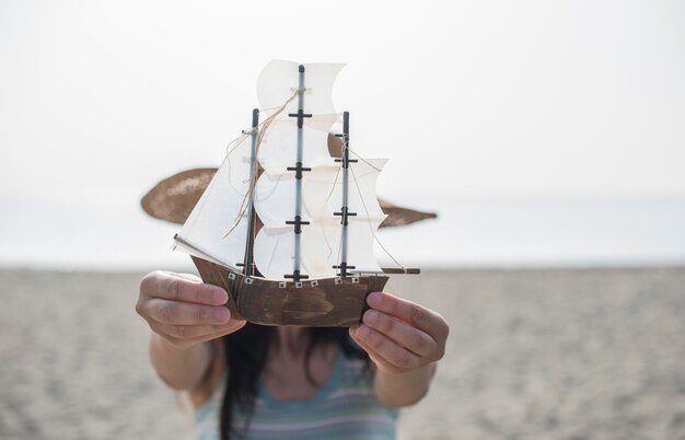 Photo woman holding toy boat at beach