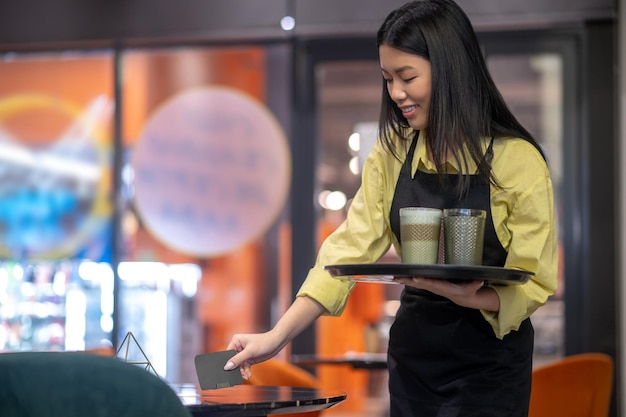 Woman holding tray of drinks and coaster