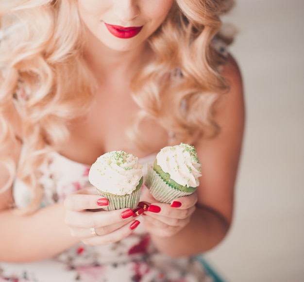 Woman holding two cupcakes with cream cheese