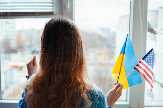 Woman holding ukrainian and american flags during war with russia invasion in ukraine russian attac