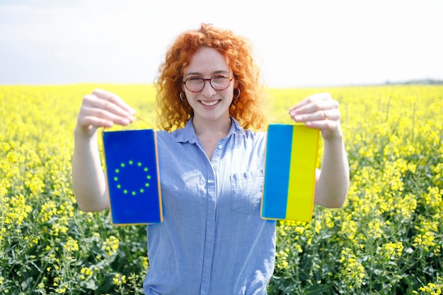 A woman holding Ukrainian and European Union flag together