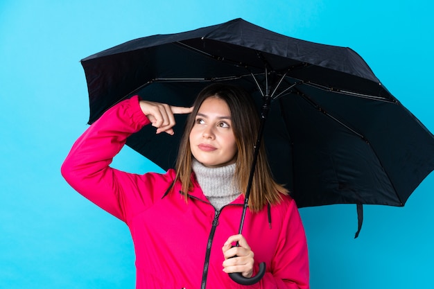 Woman holding a umbrella over isolated blue wall