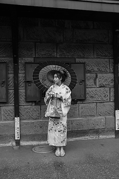 Photo woman holding umbrella standing against built structure