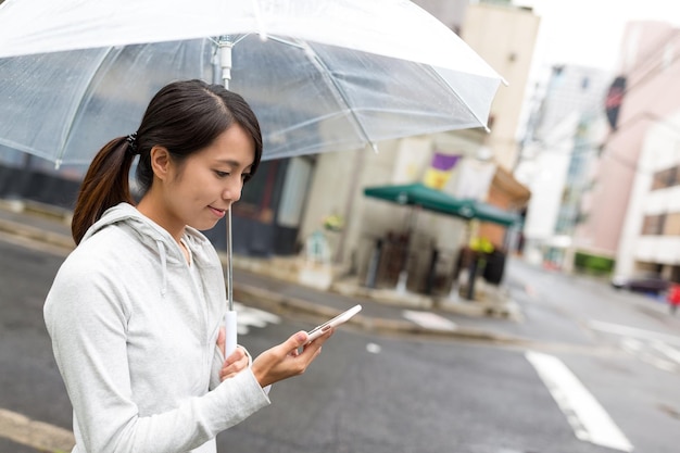 Женщина держит зонтик и пользуется мобильным телефоном в городе Хиросима