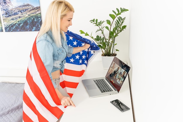 woman holding usa flag and video by laptop.