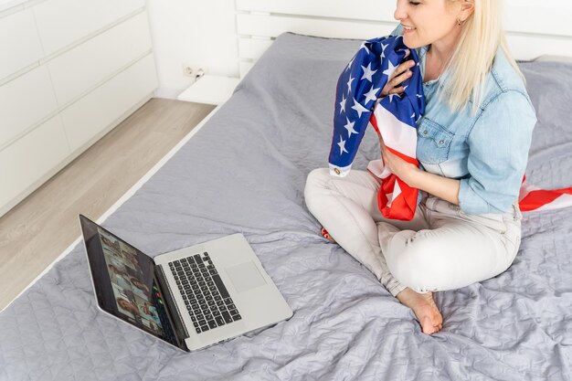 woman holding usa flag and video by laptop.