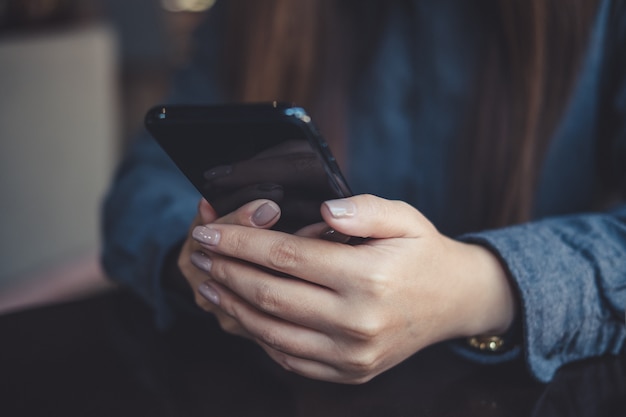 a woman holding, using and looking at smart phone on table