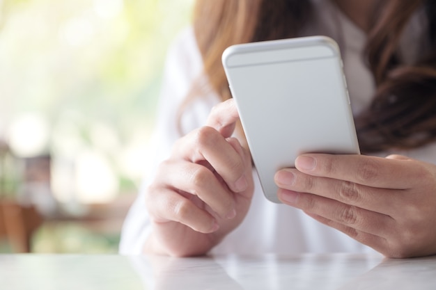 Una donna che tiene, usando e guardando lo smart phone