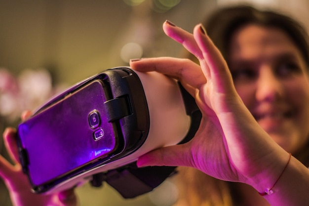 Photo woman holding virtual reality simulator in illuminated room