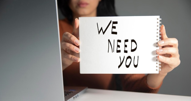 woman holding we need you text