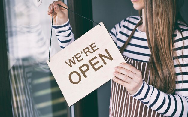 Photo woman holding we're open sign