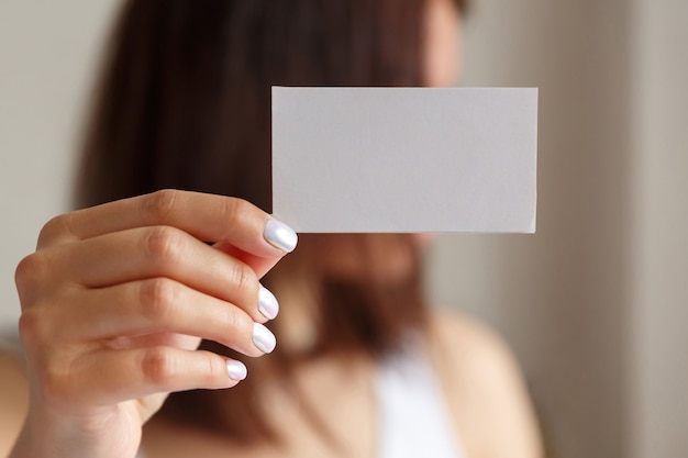 Woman holding a white business card in his hand, close up. Empty space for text