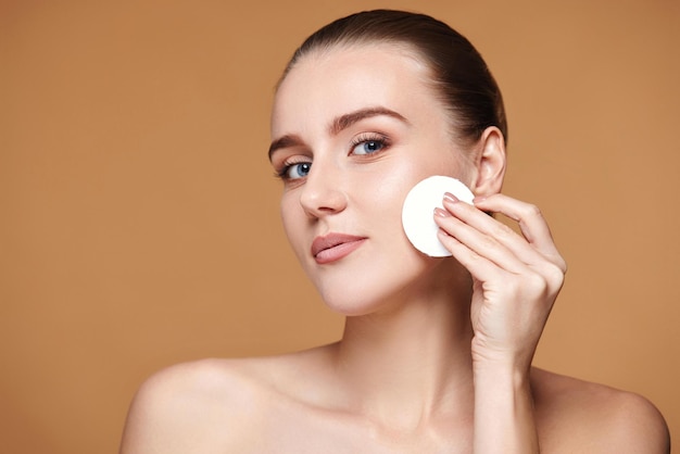 Woman holding white cotton pad with micellar water