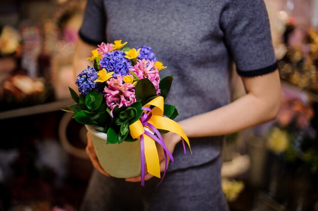 Donna che tiene un vaso di fiori bianco con giacinti colorati