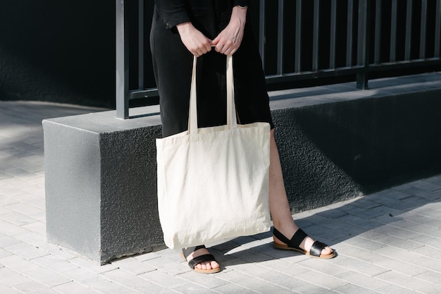 Foto donna che tiene una borsa ecologica in tessuto bianco sullo sfondo urbano della città ecologia o concetto di protezione dell'ambiente borsa ecologica bianca per mock up