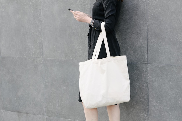 写真 都市の背景に白い繊維のエコ バッグを持つ女性生態学または環境保護の概念モックアップ用の白いエコ バッグ