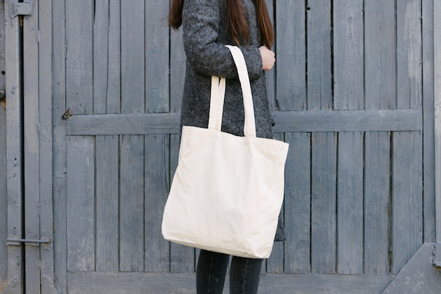 Фото Женщина, держащая белую текстильную эко-сумку в городском районе