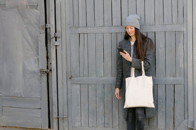 Photo woman holding white textile tote eco bag in urban area