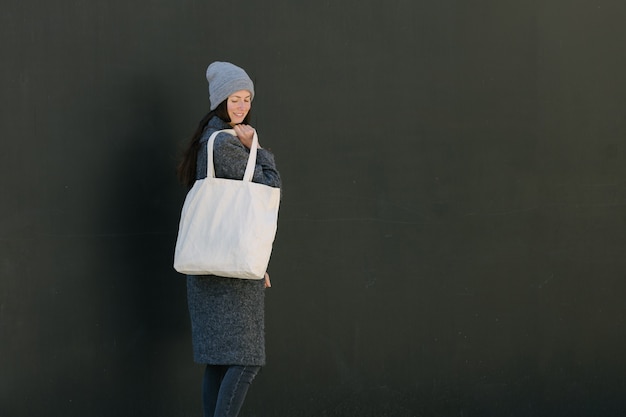 Woman holding white textile tote eco bag in urban area