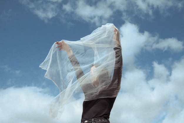 写真 雲の空に立っている白い維を握っている女性