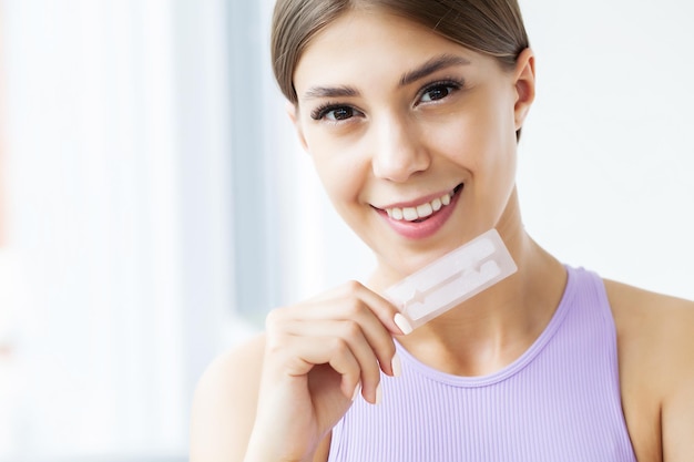 Woman holding a whitening strip.