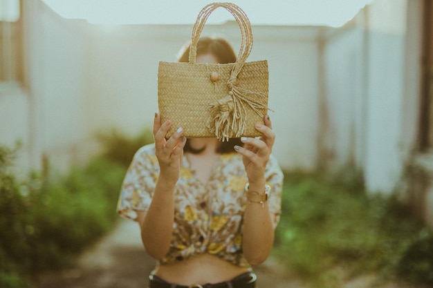 Photo woman holding wicker bag while standing outdoors