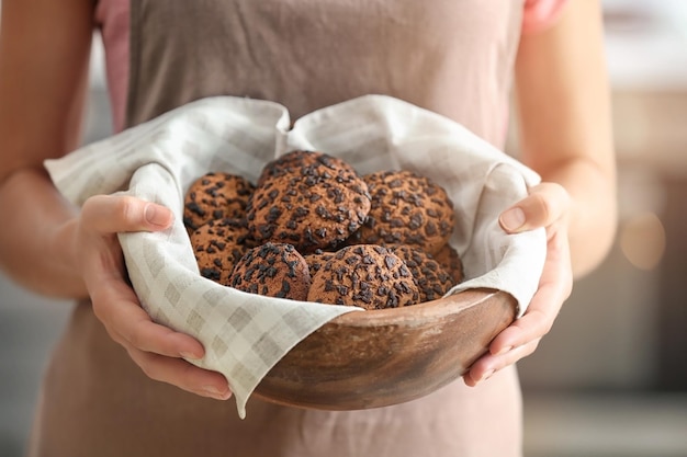 Woman holding wooden bowl with chocolate chip oatmeal cookies closeup