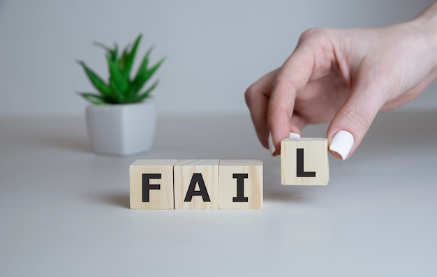 woman holding a wooden cubes with text FAIL