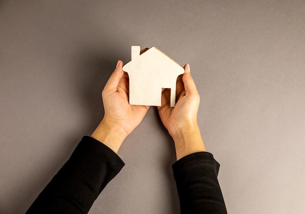 Woman holding a wooden house in her hand