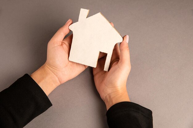 Woman holding a wooden house in her hand