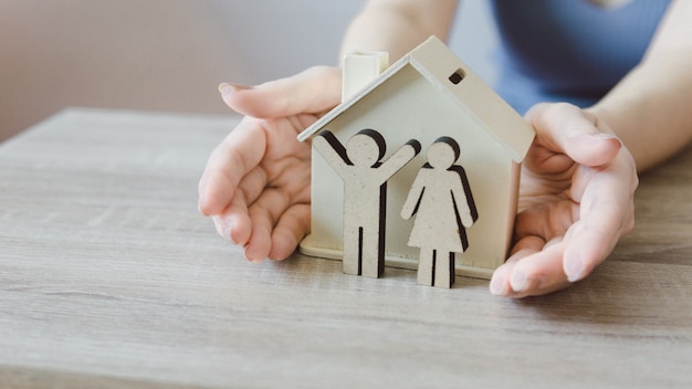 Woman holding wooden model house in hands, family