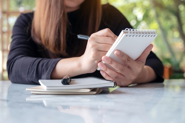 A woman holding and writing on notebook