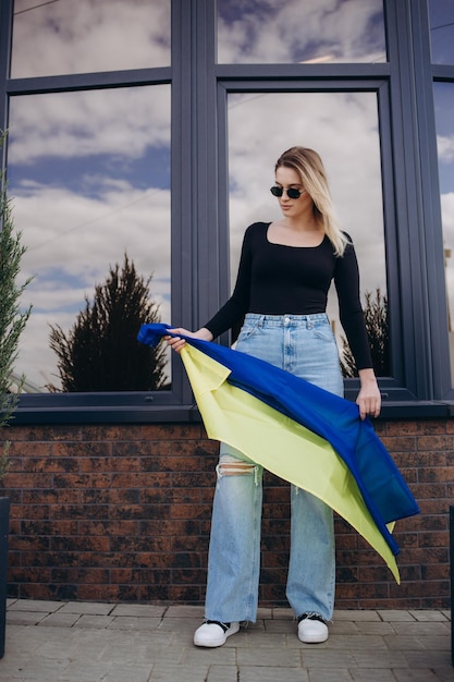 Woman holding a yellow and blue flag of ukraine in outdoors\
independence day flag day constitution day woman in traditional\
embroidery with flag of ukraine