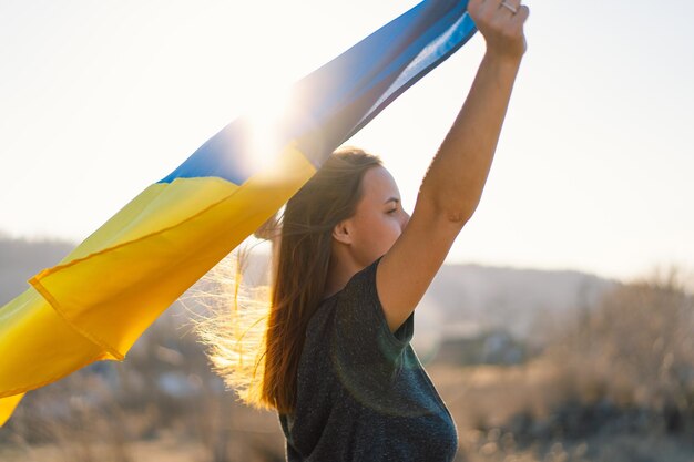 Woman holding a yellow and blue flag of ukraine in outdoors