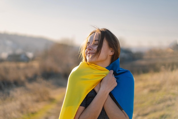 屋外でウクライナの黄色と青の旗を保持している女性