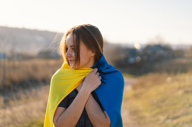 Woman holding a yellow and blue flag of ukraine in outdoors