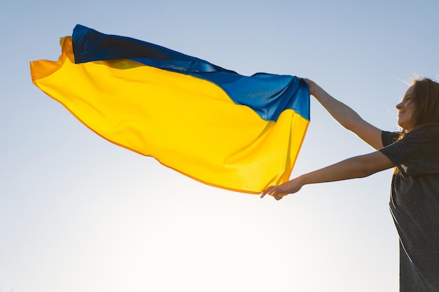 Photo woman holding a yellow and blue flag of ukraine in outdoors