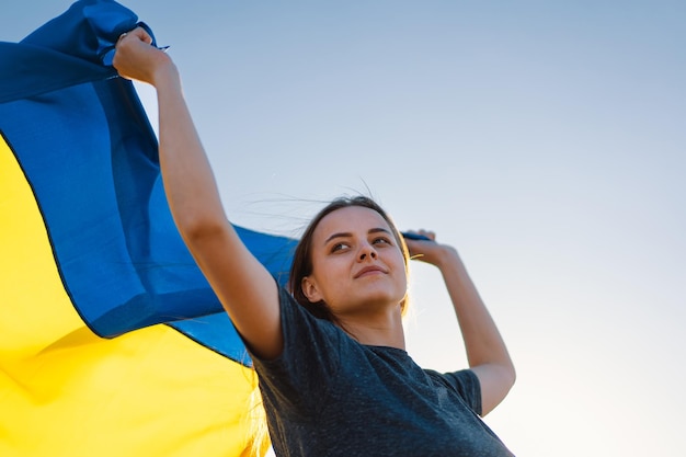 Woman holding a yellow and blue flag of Ukraine in outdoors