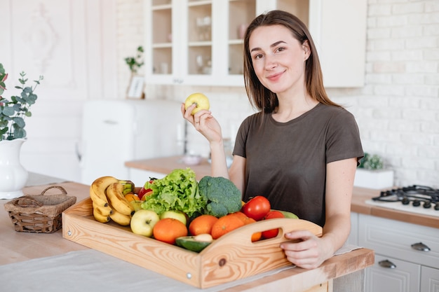 Woman holds an apple in the kitchen