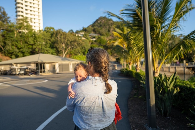 A woman holds a baby on a street