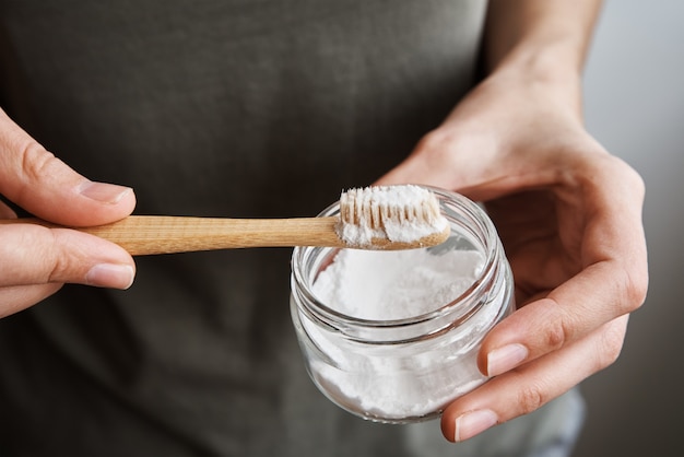 Woman holds bamboo toothbrush and tooth powder