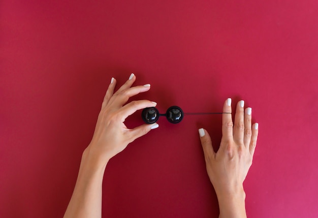 Photo a woman holds black vaginal balls ready for muscles exercises. strong vaginal muscles