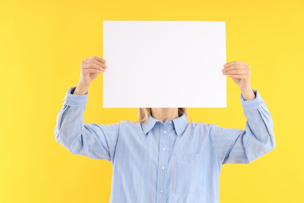 Woman holds blank banner on yellow background