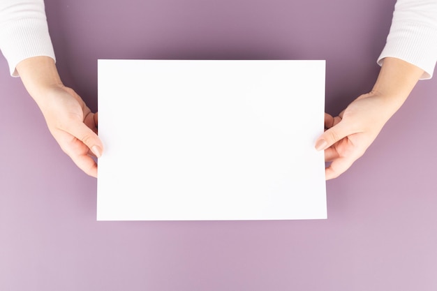 a woman holds a blank sheet of paper in her hands Advertising space