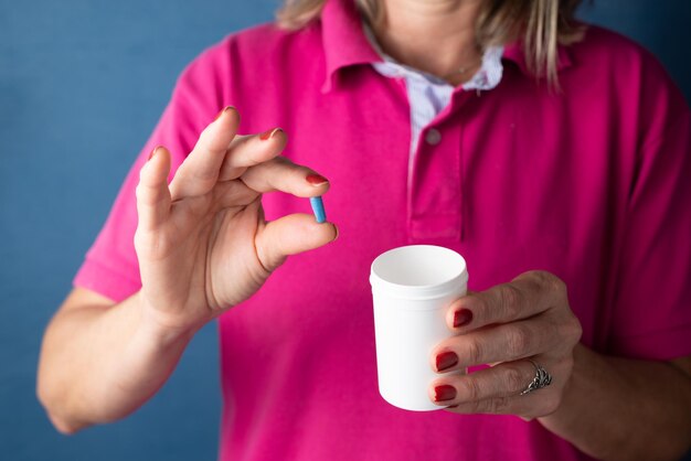 A woman holds blue pills in her hand against a blue background medical supplies