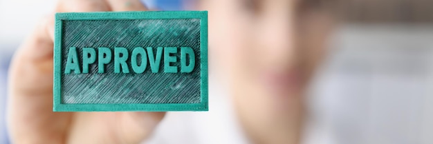 A woman holds a blue stamp inscription approved closeup