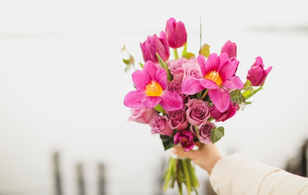 女性はピンクの花の花束を持っています。